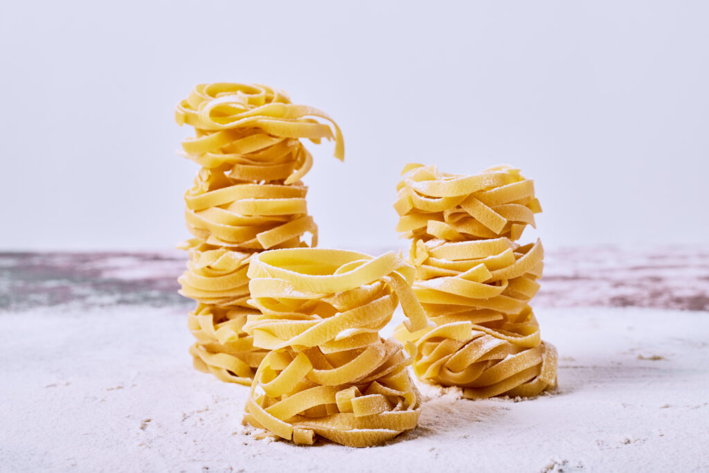 Raw fettuccine on grey background