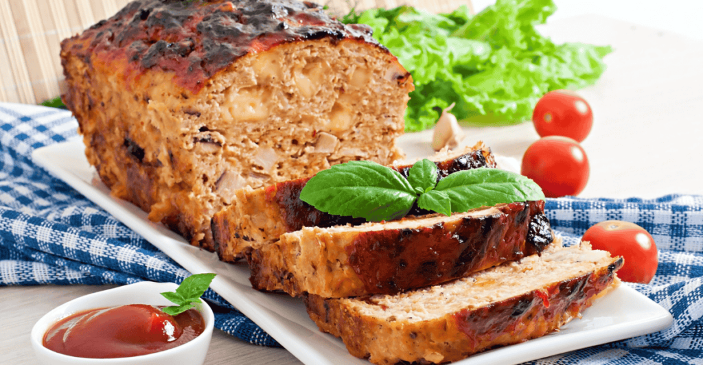 Juicy meatloaf garnished with parsley on a white platter.
