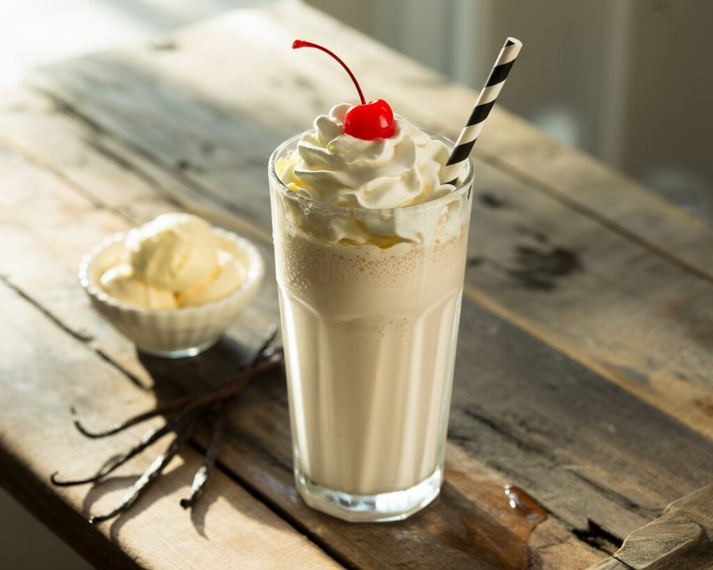 Creamy vanilla milkshake in a tall glass with a straw