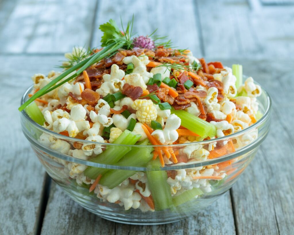Homemade popcorn salad in mixing bowl with serving spoon